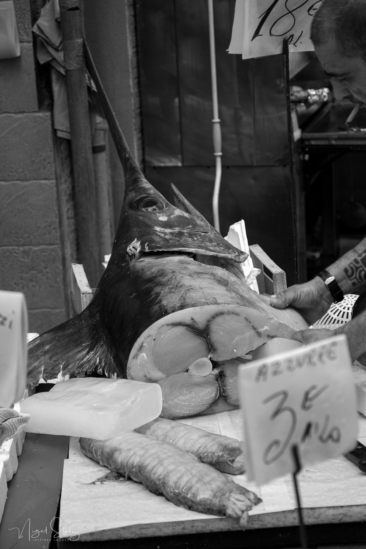 Black and white photograph shot in Naples, Italy. A fish stall with half a Marlin for sale on a marble bench. Nigel Sloley Photography