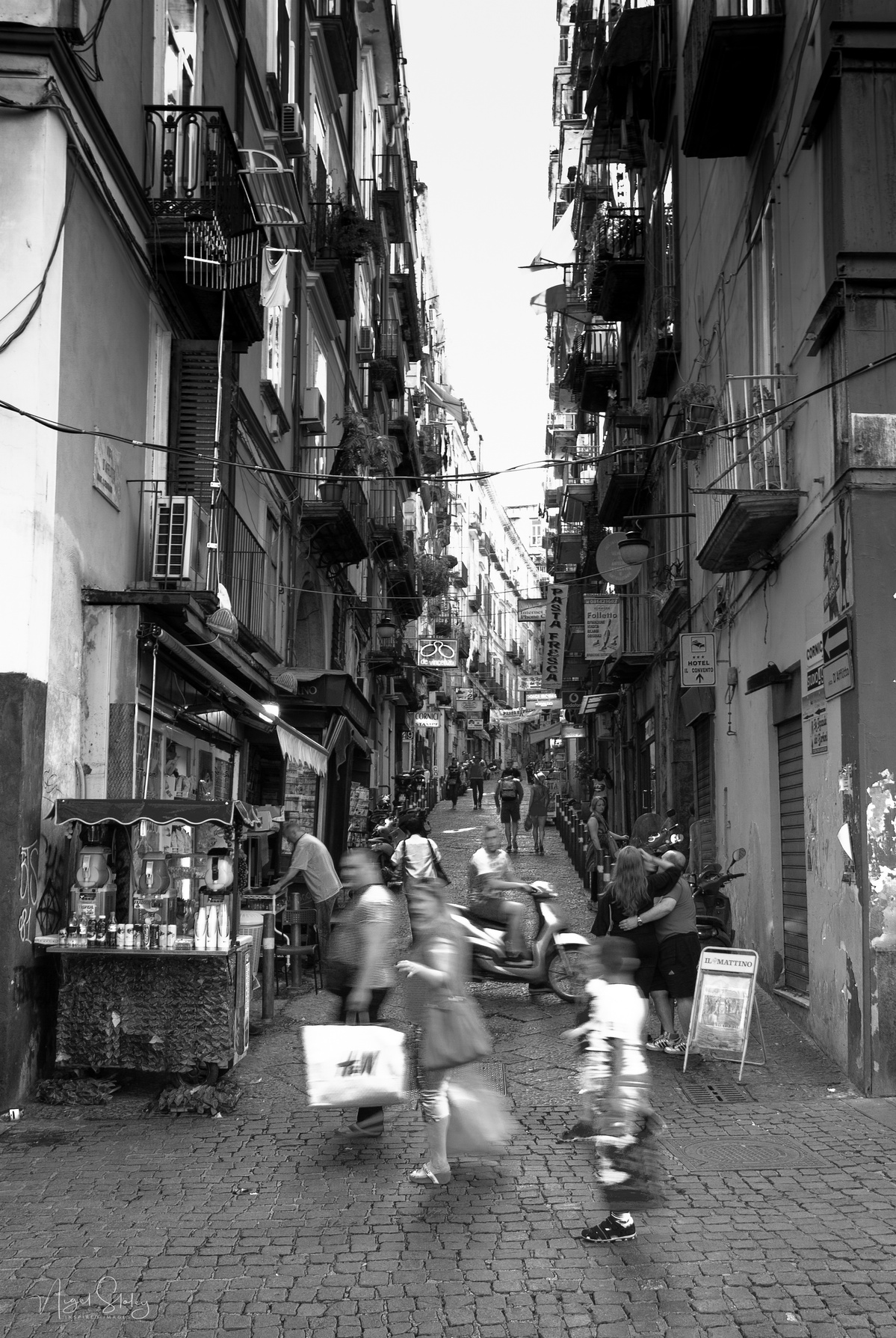 Black and white photograph shot in Naples, Italy. A very narrow street in the old town of Naples. Nigel Sloley Photography