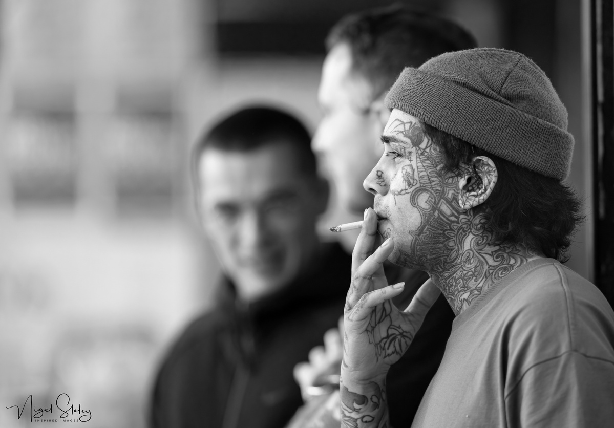 Portrait of tattoo artist at Cuba Street Tattoo taking a break during Cuba Dupa carnival shot by Nigel Sloley Photography at New Zealand's Cuba Dupa Street carnival in Wellington.
