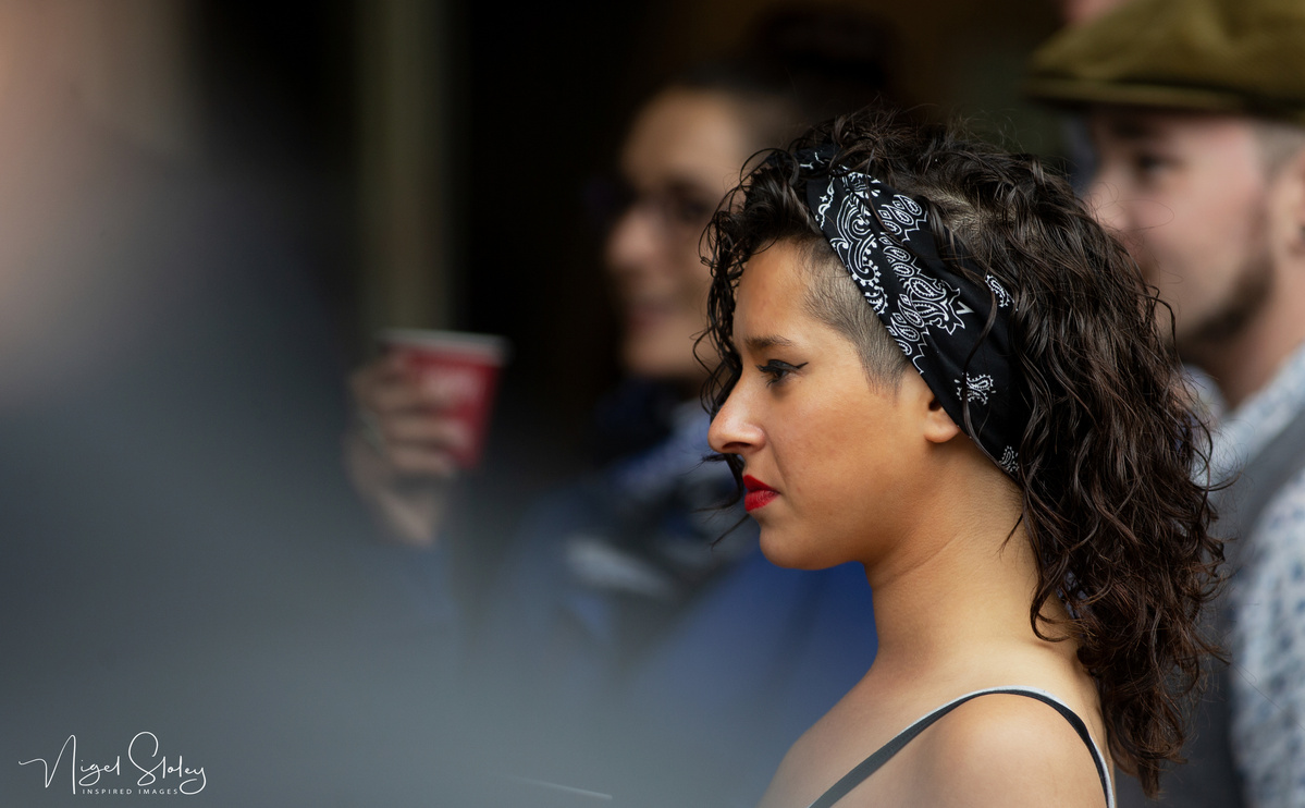 Portrait of a young woman with long curly dar hair tied with a black and white scarf shot by Nigel Sloley Photography at New Zealand's Cuba Dupa Street carnival in Wellington.