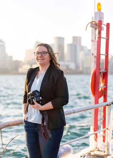 Image of photographer Samantha Jackson on the Toronto waterfront. She holds a camera and is dressed professionally.