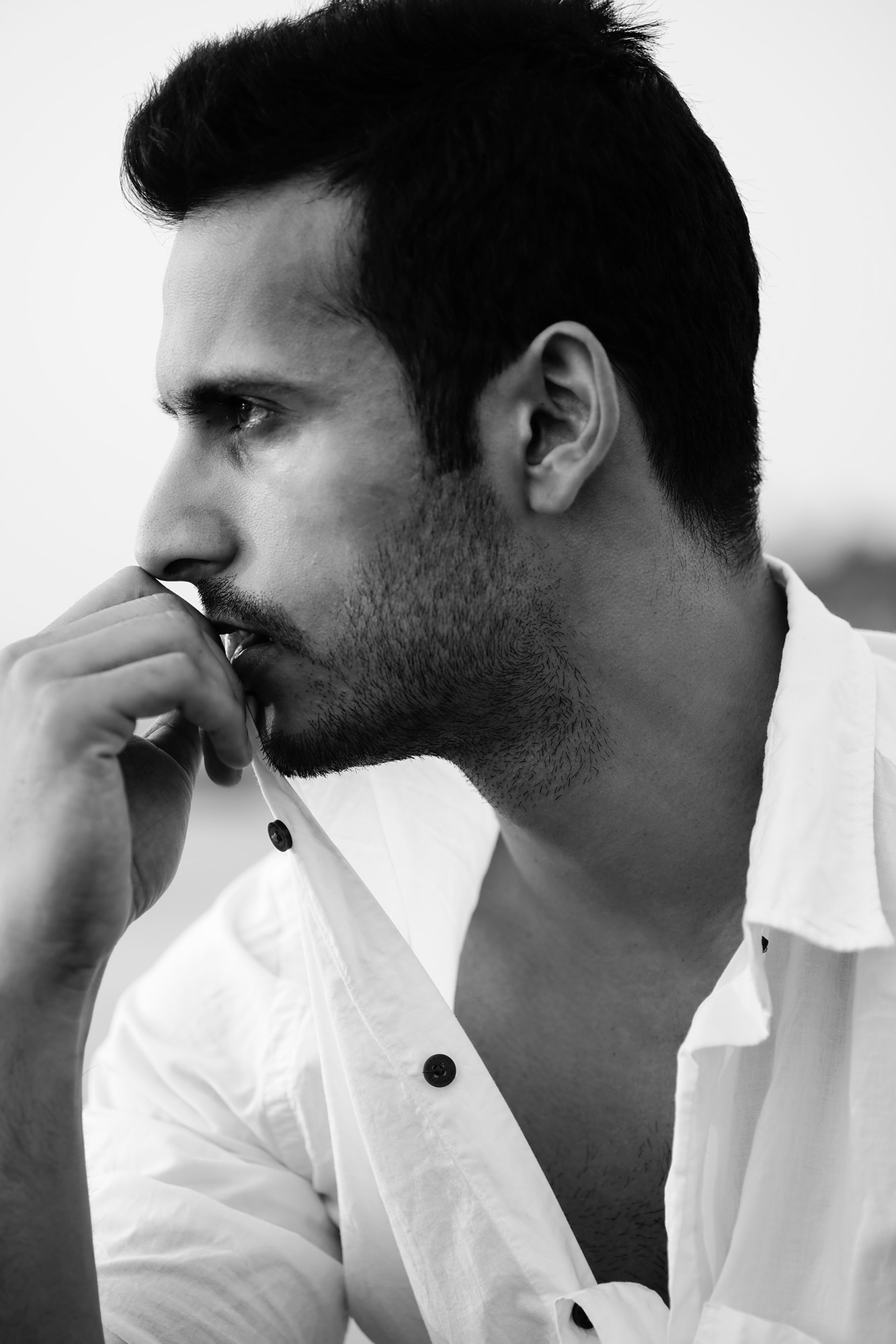 black and white portrait of male model angel singh wearing white shirt sitting on a beach photoshoot with leading fashion photographer ashish gurbani based in mumbai india