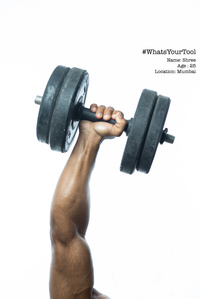 a bodybuilder and trainer proudly holds up a dumbbell as his pride and honour of his profession for concept photography shoot by top indian advertising photographer based in mumbai india