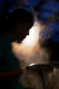 candid photograph of the silhouette of a female's side profile taken in a dark setting with one light and smoke blurred in the background with a dark blue ceiling professionally shot by best candid photographer ashish gurbani