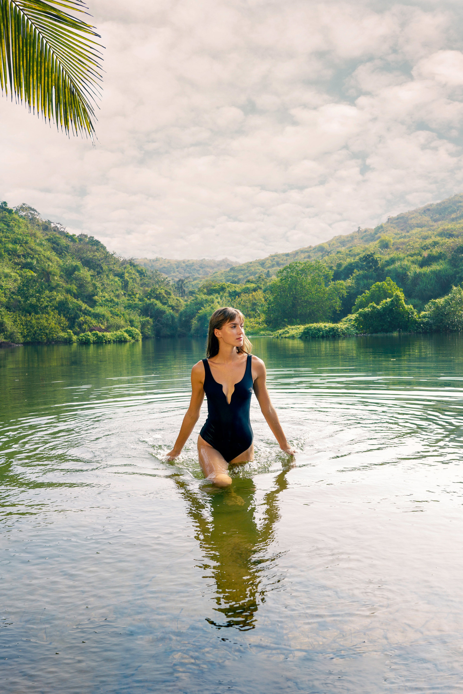 a female model walking out of a beautiful backwater lake in her swimsuit model amidst the green lucious goan jungles photographed by leading commercial photographer based in Mumbai india