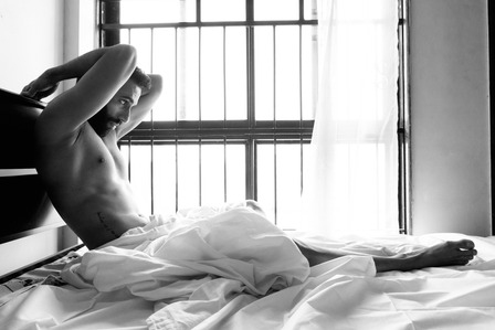 male model sitting by window bed posing for camera shot by best fine art photographer based in mumbai India