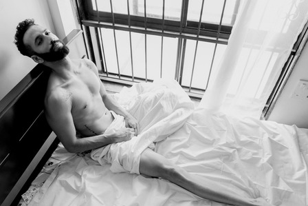 male model sitting by window bed posing for camera shot by top fine art photographer based in mumbai India 