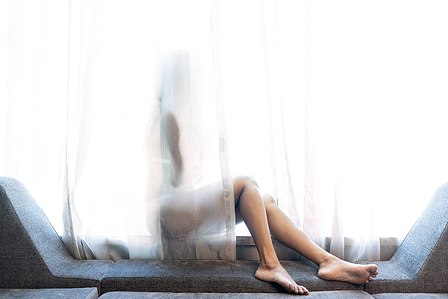 female model lost in thoughts sitting by white curtains suffering from depression photography conceptual shoot by leading advertising photographer in mumbai india