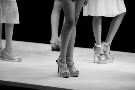 a black and white photograph of the legs of female models standing on a ramp for a fashion show professionally shot by best commercial photographer ashish gurbani based in pune india