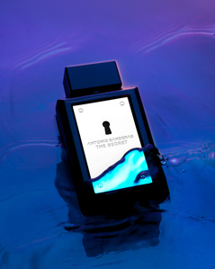 a black perfume bottle placed on water ripples neon purple lights for a branding campaign by leading still life photography studio