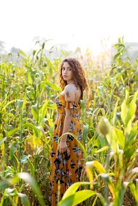 A Portrait Photo taken in an outdoor setting of a girl with curly brown hair wearing a pretty yellow dress walking through a field
shot by leading fashion photographer based in Pune, India
