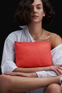 A beautiful orange bag which is plant-based has been placed on a girl's lap posing for one of India's best campaign photographer based in Pune India