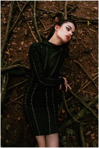 portrait photoshoot of a female model wearing a long sleeve black dress lying down on branches in an outdoor setup shot by leading fashion photographer based in pune, india