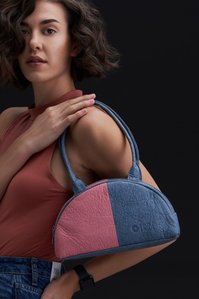 A model where is the dual-tone plant-based bag and poses for the camera with beautiful curly hair