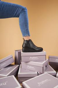 lifestyle shoot of many boxes with a leg wearing black boots in mumbai
