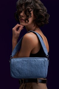 A blue plant-based leather bag hanging on the model shoulder with curly hair posing for one of India's best lifestyle photographer based in Pune India