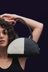 A dual tone black and white bag is being held by a model posing for the camera