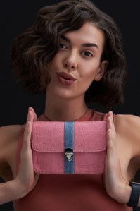 A model pouts looking at the camera holding a dual-tone bag