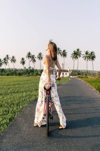 A beautiful female tourist rides a top a cycle around the luscious green fields of goa for brand campaign of the westin hotel marriott bonvoy group photographed by emerging lifestyle photographer based in Mumbai India.