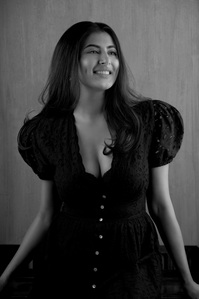 a beautiful model poses in front of a textured wall smiling into the studio lighting photography by best advertising photographer based in pune india