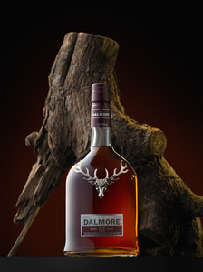 a golden deer Dalmore bottle in a conceptual stylized photoshoot with wooden log photographed by a leading perfume photographer based in Pune india