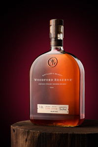 a beautiful bottle of woodford reserve kept on a wooden bark of a tree lit in studio setup with broncolour equipment by leading whiskey and beverage photographer based in pune india