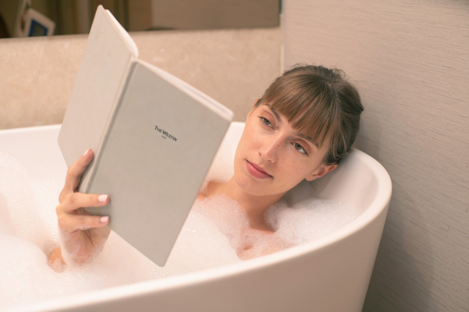 a gorgeous model laying down in the tub enjoying a read of the Westin goa hotel book menu photographer by the top hospitality and hotels photographer based in mumbai india