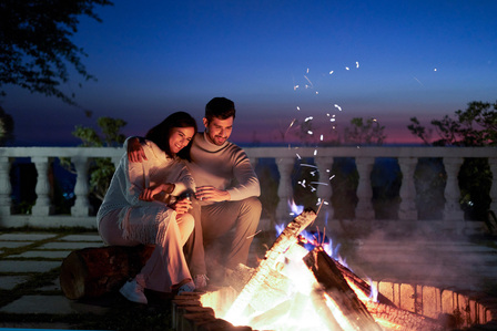 a couple enjoys the warmth of a bonfire experience creating photos for advertising
