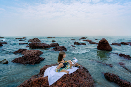 A gorgeous female sitting in a surreal setting on the rocks reading her favourite book for the zen mode on westin Goa advertising campaign photoshoot by best lifestyle photographer based in Mumbai  India.
