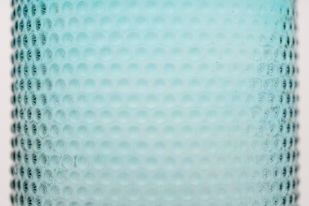 a professional photoshoot taken in a studio setting of part of the body of a blue transparent bottle shot in a close up angle by best advertising photographer ashish gurbani based in pune india