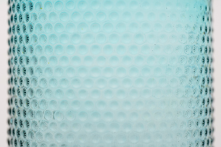 a professional photoshoot taken in a studio setting of part of the body of a blue transparent bottle shot in a close up angle by best advertising photographer ashish gurbani based in pune india