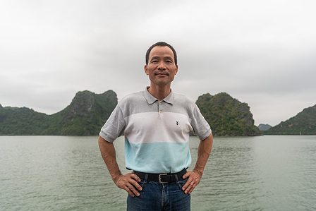 a landscape photograph of a Vietnamese man standing in front of a river and hills under a cloudy sky professionally shot by best landscape photographer ashish gurbani based in pune india