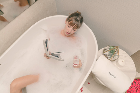 a beautiful female indian model laying down in a bubble bath tub enjoying reading a book shoot by best campaign hospitality photographer based in mumbai india