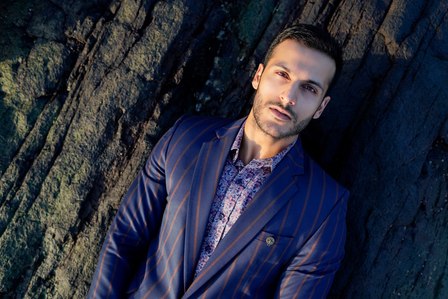 fashion male model angel singh posing for leading mens wear clothing designer brand lying down on rocks on a cool blue beach during summer conceptual photoshoot with best advertising photographer based in delhi india