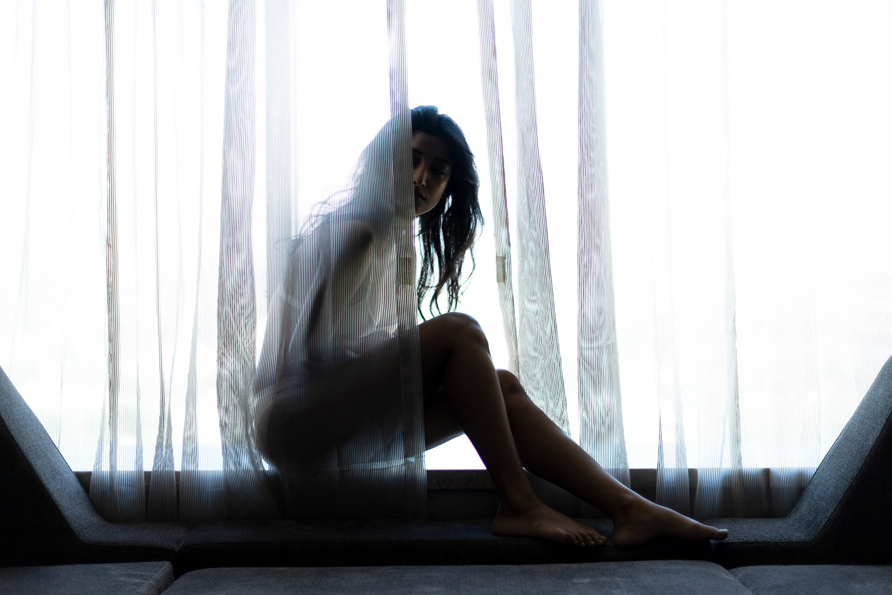 a female model sitting behind a curtain peeping into the darkness for a photoseries on anxiety and depression shot by leading indian lifestyle photographer based ib mumbai india