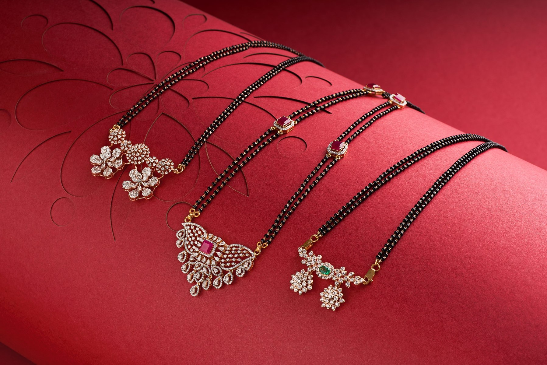 three gold mangal sutras on a magenta colour background shot in a photo studio setup by pune based top jewellery photographer specializing in still life work
