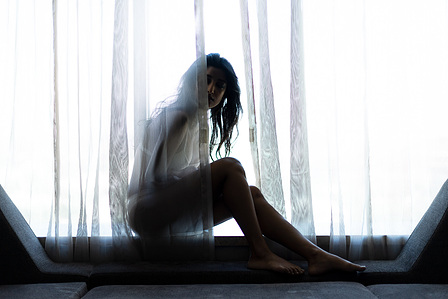a female model sitting behind a curtain peeping into the darkness for a photoseries on anxiety and depression shot by leading indian lifestyle photographer based ib mumbai india