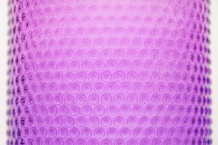 a close up photograph of a pink transparent bottle professionally shot in a studio setting with a white background taken by best creative photographer ashish gurbani based in pune india