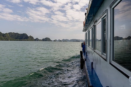 professional photo taken in landscape form of the outer side of a ferry boat over harsh waves with a blue sky clouds and hills in the background shot by best creative photographer ashish gurbani based in pune india