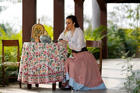 farm girl sitting on a well-styled dining table having lunch with russtic jewe on her farm land in a Heidi themed photoshoot for clothing brand advertising campaign shot by leading advertising photographer based in pune india