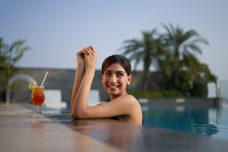 a beautiful girl poses in a swimming pool during sunset to capture photos for advertising campaign shoot in mumbai india