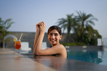 a beautiful girl poses in a swimming pool during sunset to capture photos for advertising campaign shoot in mumbai india