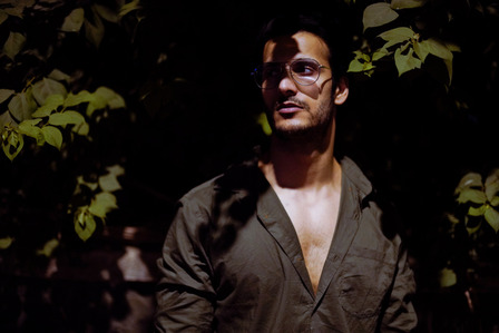 professional photoshoot of a male fashion model hiding in concept shoot of light and shadows formed by trees on the road by top fashion and advertising photographer ashish gurbani based in mumbai india