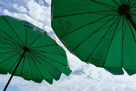 landscape photograph of two green umbrellas with a blue sky and clouds in the background professionally shot by top still life photographer ashish gurbani based in pune india