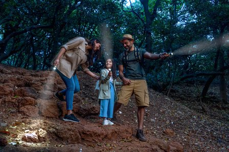 husband and wife walking in jungle with their little daughter trekking in the jungle with torch lights for advertising campaign photoshoot marriott bonvoy group photoshoot by best advertising and lifestyle photographer