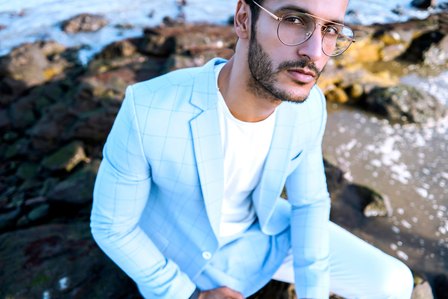 top fashion male mode angel singh sitting on the rocks with blue suit by the blue beach showcasing mens wear summer collection by clothing designer brand photography by top advertising photographer based in mumbai india
