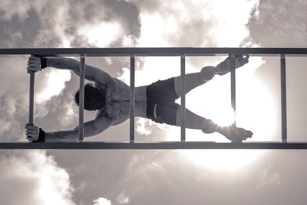 conceptual black and white photoshoot of fitness model posing on ladder doing yoga pose shoot with leading advertising photographer specialising in fitness photography based in mumbai india