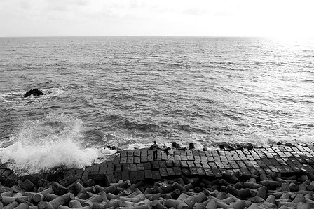 monochrome black and white photograph of man standing by the ocean during sunset shot by indias top advertising photographer based in mumbai