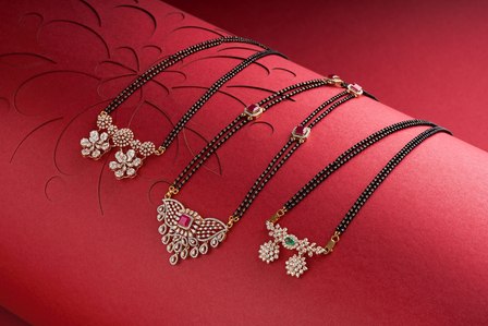 three gold mangal sutras on a magenta colour background shot in a photo studio setup by pune based top jewellery photographer specializing in still life work