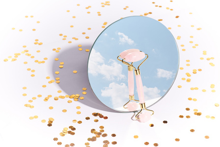  A professional product studio photoshoot of a round mirror reflecting the sky concept photoshoot of a luxury rose quartz face roller by leading cosmetic product photographer ashish gurbani based in pune india